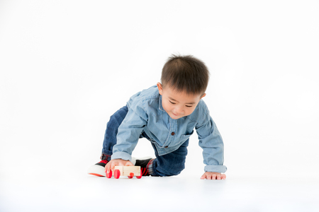 One year old Asian baby boy in jeans shurt sitting on floor playing with toy funny isolated on white background studio shot.の写真素材
