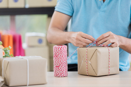 Asian businessman in casual shirt was is packing parcels, working in simple house office look like doing startup business. Concept for online marketing, SME and home base workplace.の写真素材