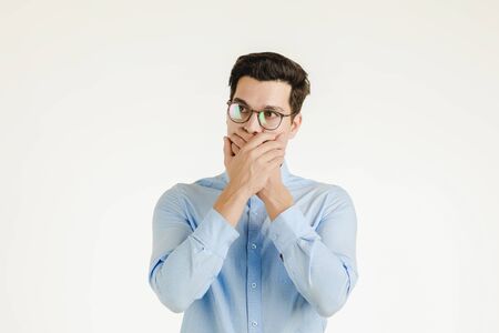 Young hipster office man covering his mout by hands as keep secret or silence sign, portrait shot isolated on white background.の写真素材
