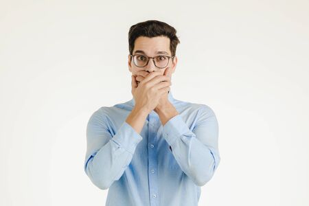 Young hipster office man covering his mout by hands as keep secret or silence sign, portrait shot isolated on white background.の写真素材