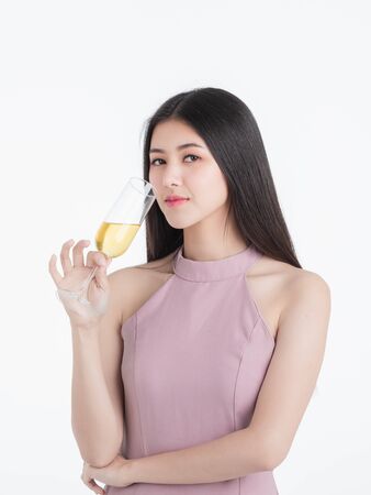 Beautiful young asian woman in pink dress, confident introvert posing with champagne glass, portrait short isolated on white background.の写真素材