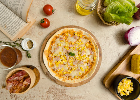 Top view closeup shot of delicious tasty juicy thin crispy cheesy corn and ham Italian pizza placed on wooden board on party table around with other ingredients, sauce, olive oil, bacon and tomatoes.の写真素材