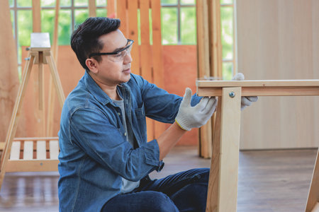 Asian male holding assembling wooden furniture in home housing building construction site.の写真素材