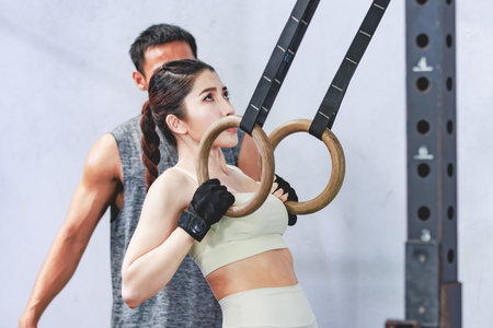 Asian young professional muscular male personal trainer teaching female fit strong body sporty...