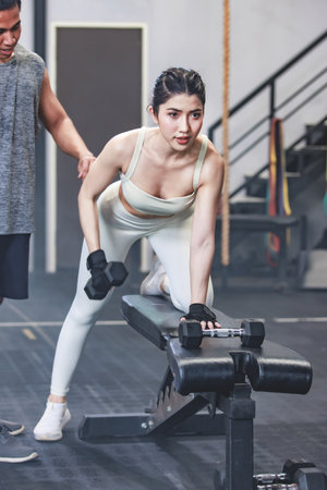 Asian professional muscular male personal trainer teaching female fit strong body sporty athletic...