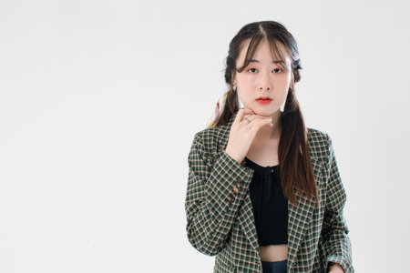 Portrait isolated cutout studio shot of Asian young cute female fashion model with pigtails braids hairstyle in casual plaid suit and crop top shirt standing posing look at camera on white background.の写真素材