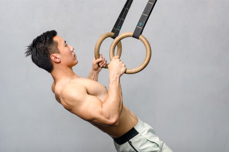 Asian strong handsome young shirtless male muscular fitness model in sporty shorts holding pushing...