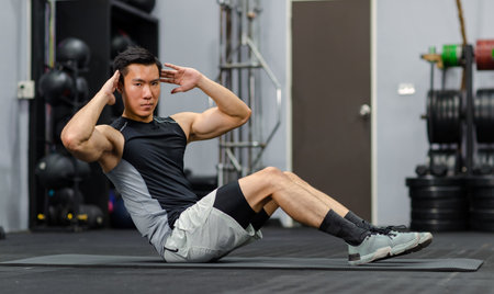 Millennial Asian strong young fit male muscular fitness model in sportswear sleeveless shirt and...