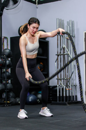 Millennial Asian strong young fit female muscular fitness athlete model in sportswear sexy sport bra...