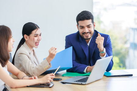 Asian Indian multinational professional successful bearded male businessman explaining discussing brainstorming with female businesswomen colleagues in formal business suit in office meeting room.の写真素材
