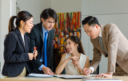 Asian professional successful male businessman manager mentor supervisor in formal business suit standing helping teaching supporting female businesswoman colleague work with laptop in meeting room.の写真素材