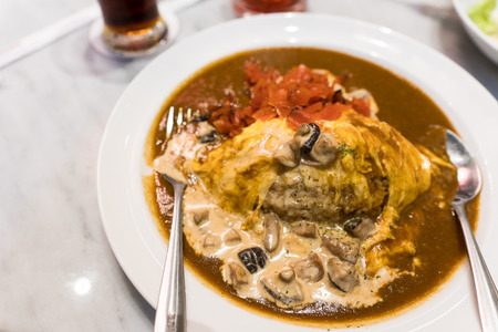 Rice and curry beef Wrapped in omelet and topped with a creamy mushroom sauce.の写真素材