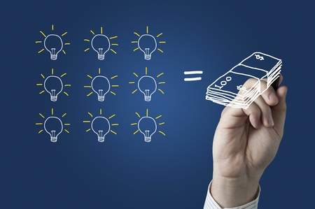 Male hand drawing a bulb and money on whiteboardの写真素材