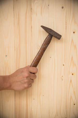 Hand with hammer on wood backgroundの写真素材