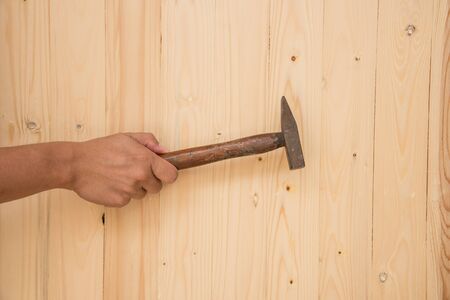 Hand with hammer on wood backgroundの写真素材
