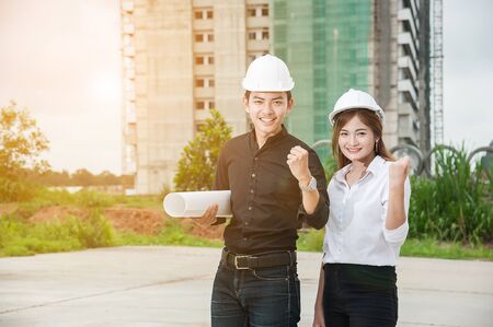 Portrait of beautiful young women and men engineer  wear a white safety helmet smiling on building construction siteの写真素材
