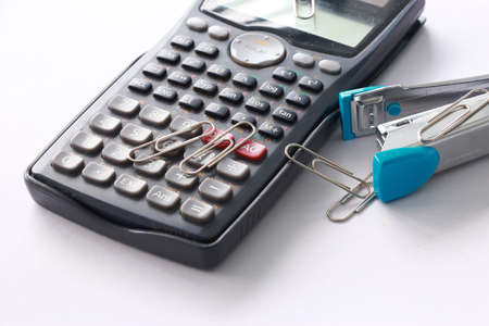 Old Calculator and Stapler with Paperclip on White Background