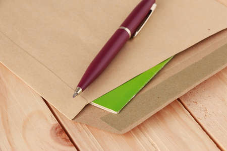 Violet Pen on Document Holder with Old Green Book on Wooden