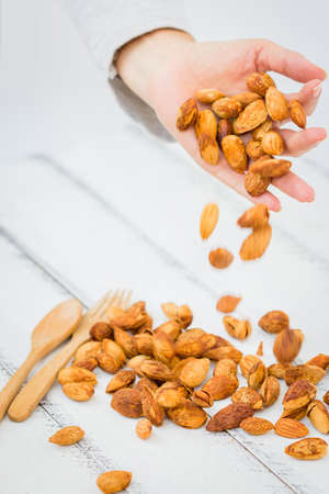 Movement of Pour Almonds From Hand to White Wooden Boardの写真素材