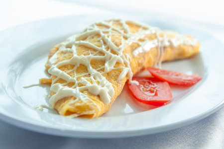 Rolled egg omelets filled with chicken garnished with mayonnaise and sliced tomatoes
