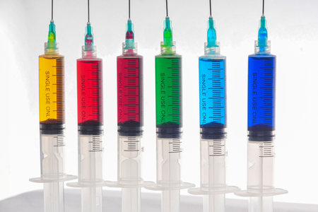 Syringes filled with colorful liquids are neatly arranged on an isolated backgroundの写真素材