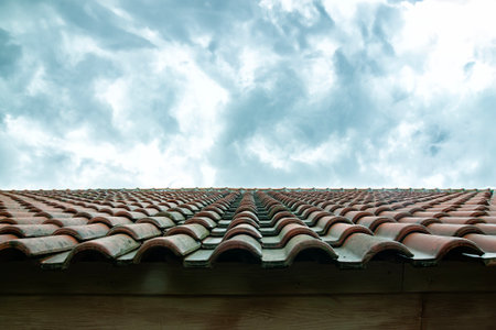 the shape of the roof of the house is made of red tiles with a bright, cloudy sky in the backgroundの写真素材