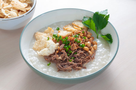 Bubur Daging Krawu Gresik contains white rice porridge with side dishes of shredded beef, fried...