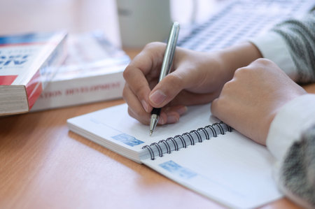 close up of hands writing on a blank book in office desk
