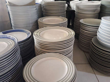 stack of plates of cleaned white, blue, plates for catering buffet in wedding &restaurant room