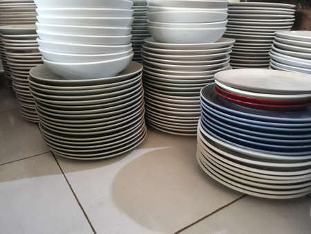 stack of plates of cleaned white, blue, red plates for catering buffet in wedding &restaurant roomの写真素材
