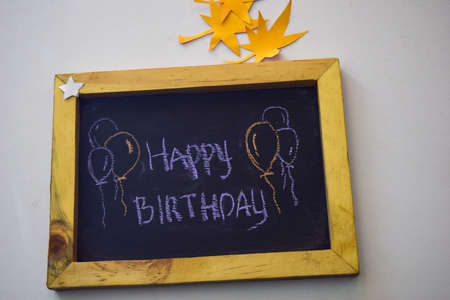 text Happy Birthday on the chalkboard and colorful chalk,autumn leaf origami. White backgroundの写真素材