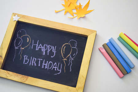 text Happy Birthday on the chalkboard and colorful chalk,autumn leaf origami. White backgroundの写真素材
