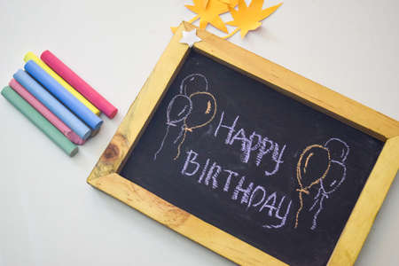 text Happy Birthday on the chalkboard and colorful chalk,autumn leaf origami. White backgroundの写真素材