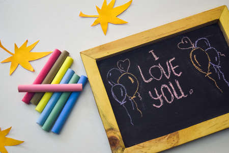 text love you on the chalkboard and colorful chalk,autumn leaf origami. White backgroundの写真素材