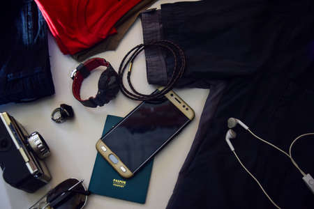 Passport, sunglasses, old camera, jeans, shirt, watches, bracelet and sunglasses are lying on white background. Preparing for travelingの写真素材