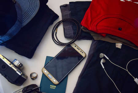 Passport, sunglasses, old camera, jeans, shirt, watches, bracelet and sunglasses are lying on white background. Preparing for travelingの写真素材