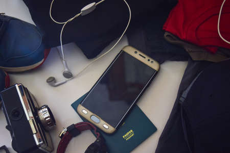 Passport, sunglasses, old camera, jeans, shirt, watches, bracelet and sunglasses are lying on white background. Preparing for travelingの写真素材