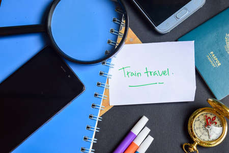 Travel Concept Inspiration - Train Travel written on paper. passport, magnifying glass, Compass, Smartphone, book on black backgroundの写真素材