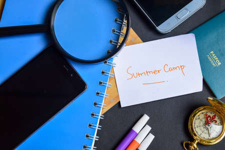 Travel Concept Inspiration - Summer Camp on paper. passport, magnifying glass, Compass, Smartphone, book on black backgroundの写真素材