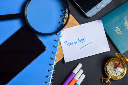 Travel Concept Inspiration - Travel Tips on paper. passport, magnifying glass, Compass, Smartphone, book on black backgroundの写真素材