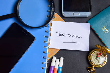 Travel Concept Inspiration - Time to Grow now written on paper. passport, magnifying glass, Compass, Smartphone, book on black backgroundの写真素材
