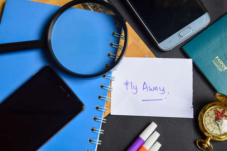 Travel Concept Inspiration - Fly Away written on paper. passport, magnifying glass, Compass, Smartphone, book on black backgroundの写真素材