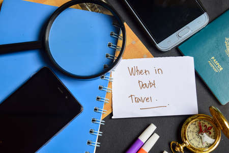 Travel Concept Inspiration - When in Doubt Travel written on paper. passport, magnifying glass, Compass, Smartphone, book on black backgroundの写真素材