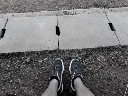 black & white. Man take picture of shoes after running in the field