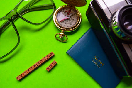 Destination sea message written on wooden blocks,travel and vacation concept. passport, smartphone, eyeglass, analog camera isolated green backgroundの写真素材