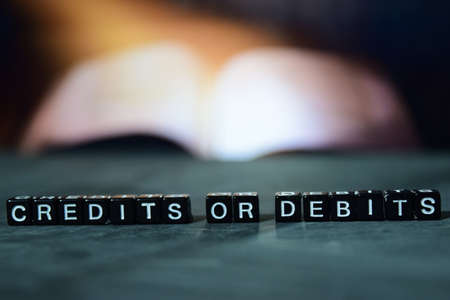 Credits or debits on wooden blocks. Business and finance concept. Cross processed image with bokeh backgroundの写真素材