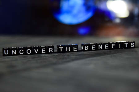 Uncover the benefits on wooden blocks. Business and finance concept. Cross processed image with bokeh backgroundの写真素材