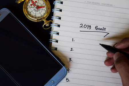 Notebook, smartphone, compass and pen, with selective focus 2019 Goals text in someone hand with black background, for business presentation ror adding your listの写真素材