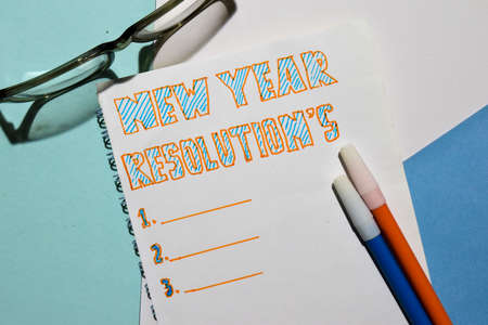 Top view New Year Resolutions text list with marker and eyeglasses for business presentation mock up...