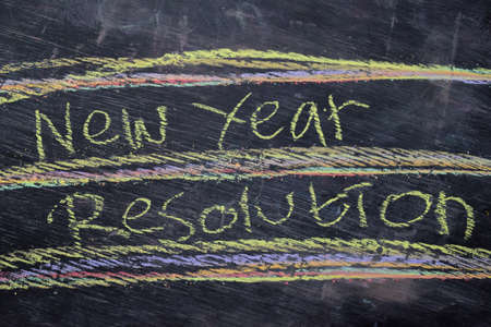 New Year Resolution handwritten text with colorful chalk on blackboard background. Inspiration,...